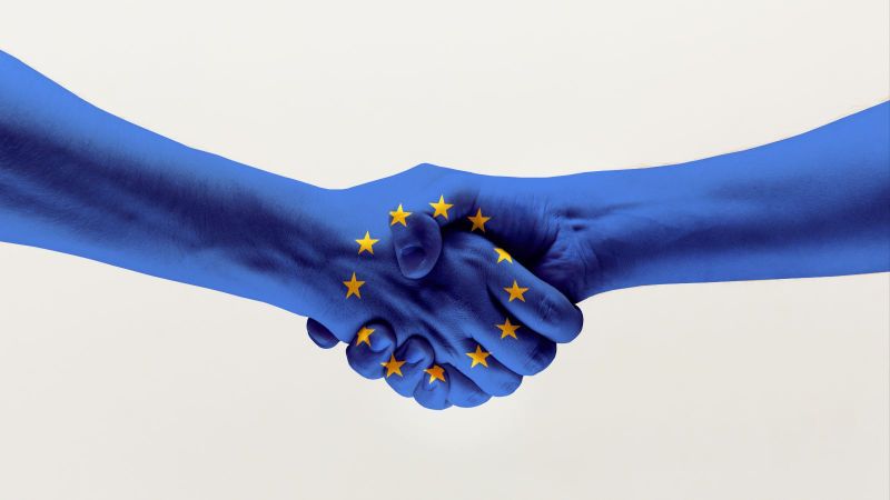 Händedruck von zwei Händen in blauer EU-Flagge