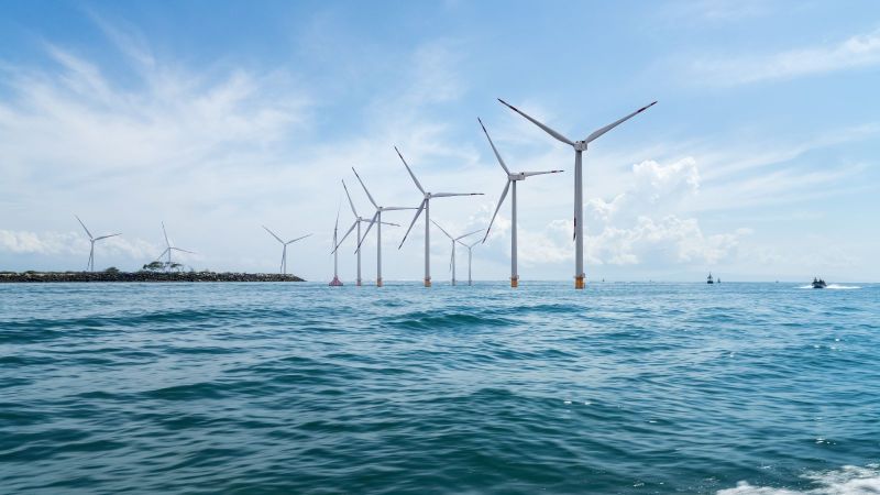 Mehrere Windräder stehen im Ozean.