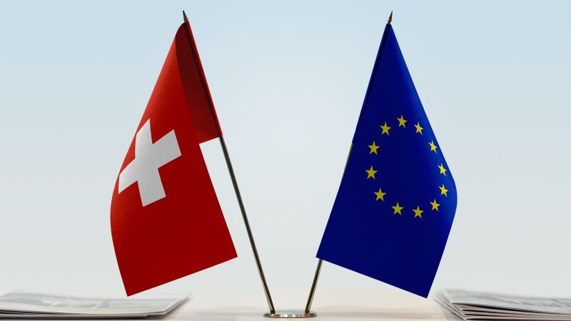 Flaggen der EU und der Schweiz stehen nebeneinander auf einem Tisch.