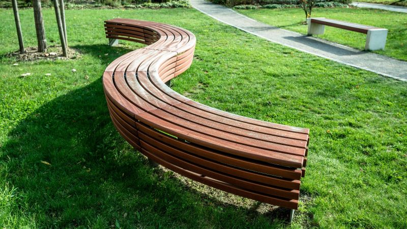 Eine gewundene moderne Holzbank auf einer Grünfläche