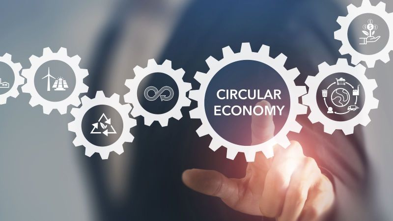 Ein Finger zeigt auf eine Reihe von illustrierten Zahnrädern mit der Beschriftung Circular Economy und mehreren Icons.