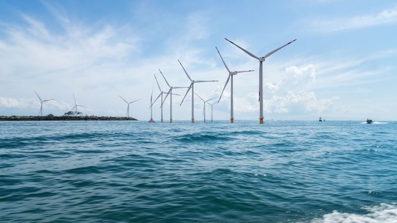 Mehrere Windräder stehen im Ozean.