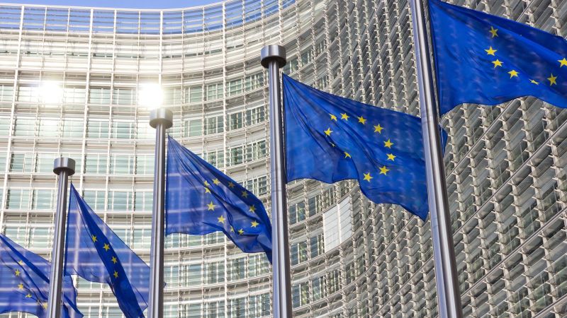 Bild des EU Kommissions Gebäude in  Brüssel mit Europa Fahnen im Vordergrund