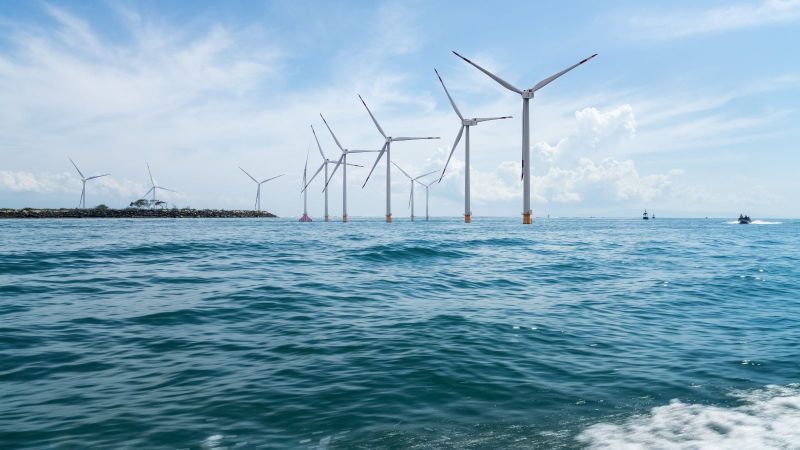 Mehrere Windräder stehen im Ozean.