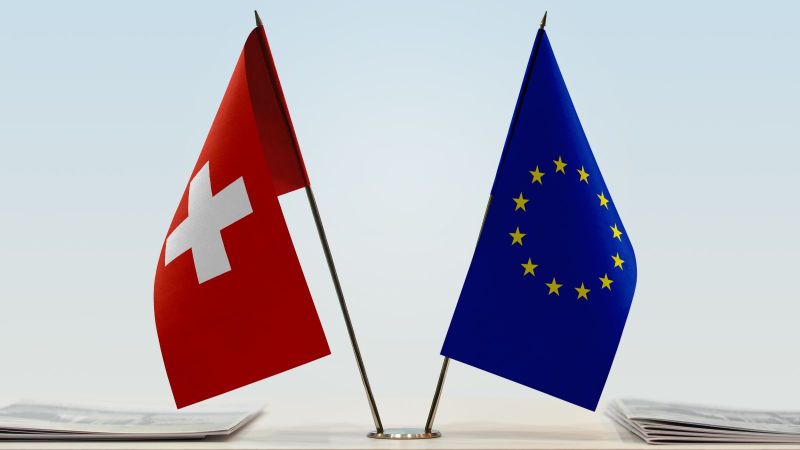 Flaggen der EU und der Schweiz stehen nebeneinander auf einem Tisch.