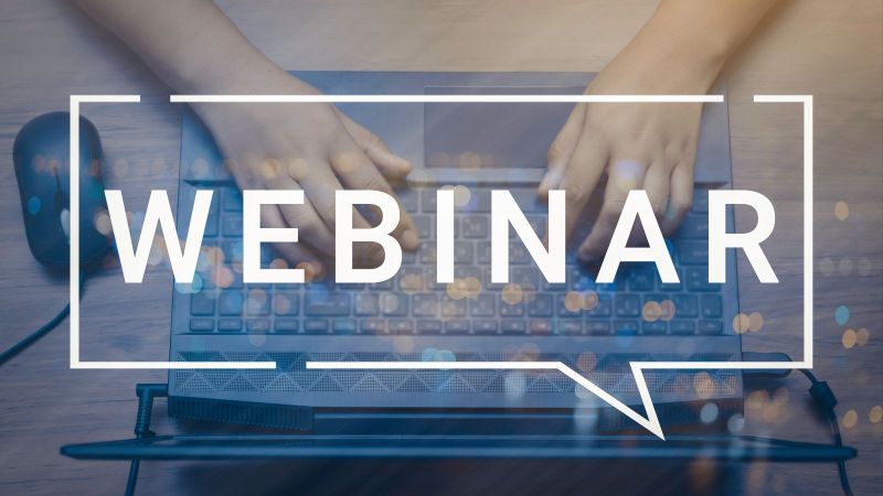 Das Wort Webinar ist über das Photo eines Laptops mit Händen aus der Vogelperspektive gelegt.