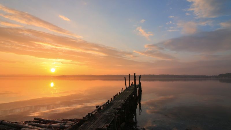 Holzsteg an einem See im Sonnenuntergang.