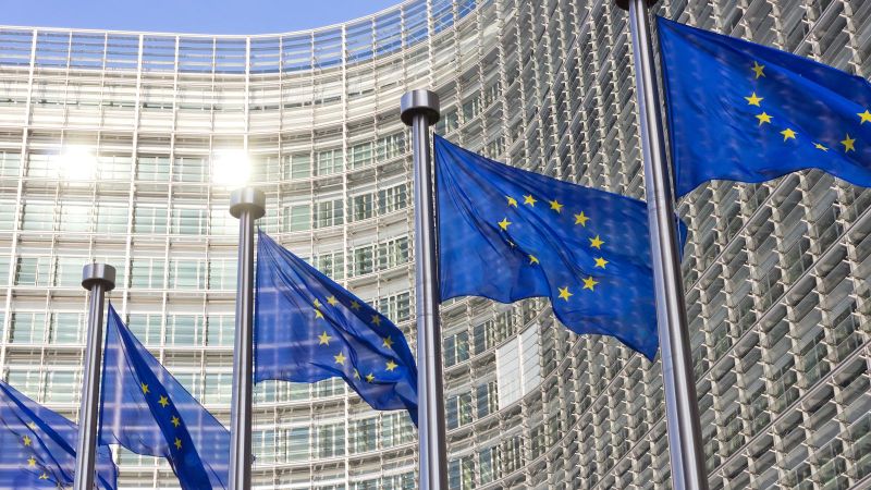 Bild des EU Kommissions Gebäude in  Brüssel mit Europa Fahnen im Vordergrund