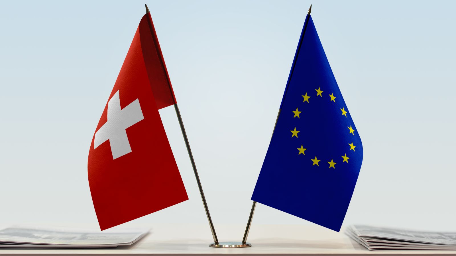 Flaggen der EU und der Schweiz stehen nebeneinander auf einem Tisch.