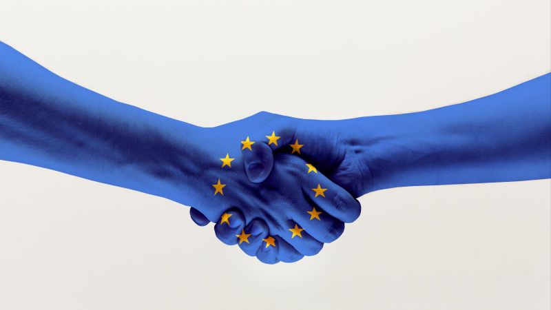 Händedruck von zwei Händen in blauer EU-Flagge