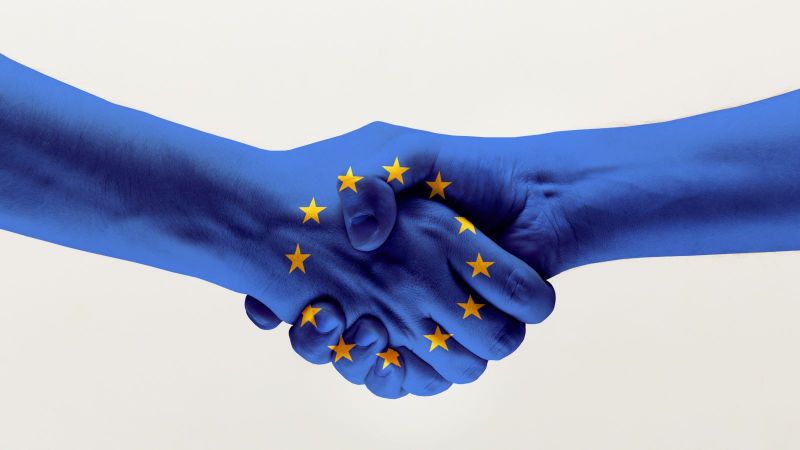 Händedruck von zwei Händen in blauer EU-Flagge