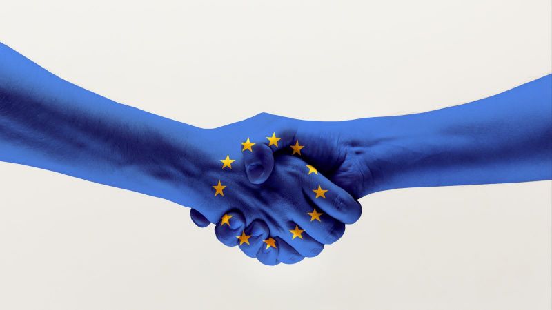 Händedruck von zwei Händen in blauer EU-Flagge