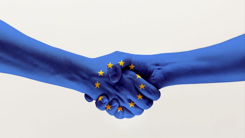 Händedruck von zwei Händen in blauer EU-Flagge