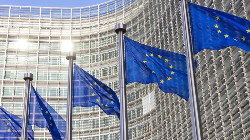 Bild des EU Kommissions Gebäudes in  Brüssel mit Europa Fahnen im Vordergrund