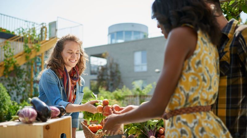Eine Frau verkauft Gemüse an einem Stand in einem Dachgarten.