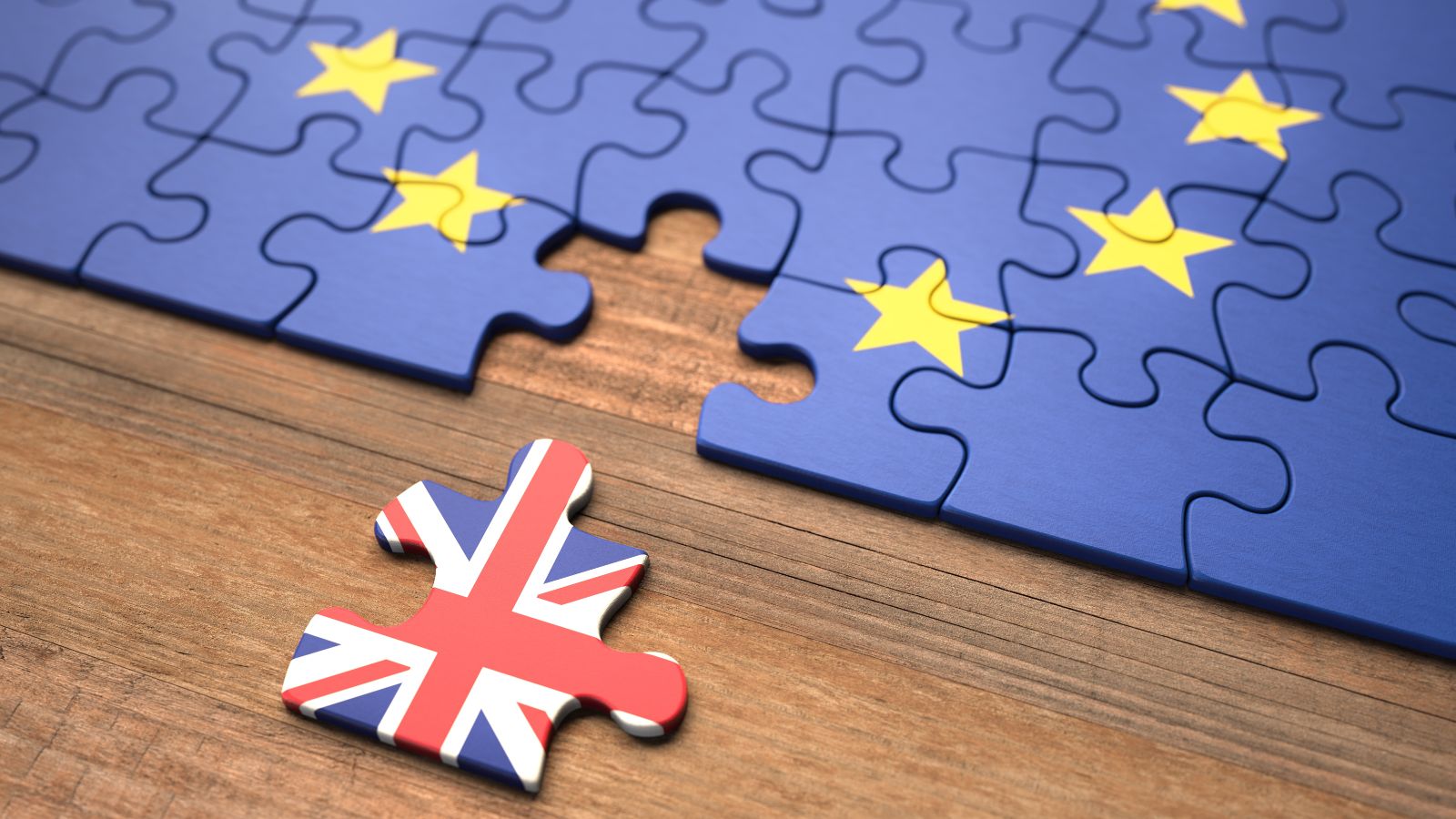 Ein Puzzle mit einer Europaflagge liegt auf einem Tisch. Ein Teil ist entfernt und zeigt die Flagge des Vereinigten Königreichs. 
