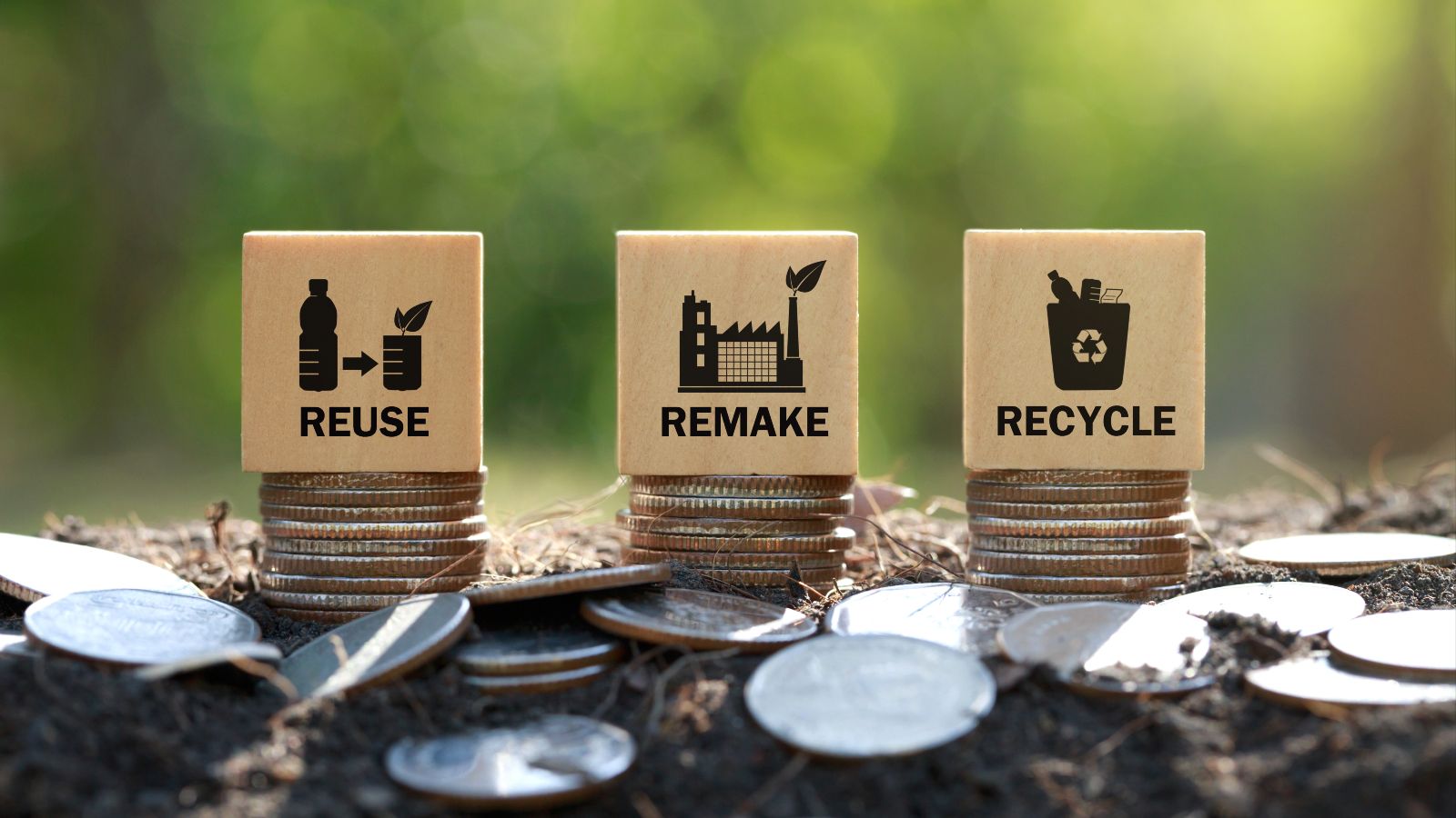Auf drei Münzstapeln steht jeweils ein Holzwürfel mit der Beschriftung „Reuse“, „Remake“, „Recycle“.