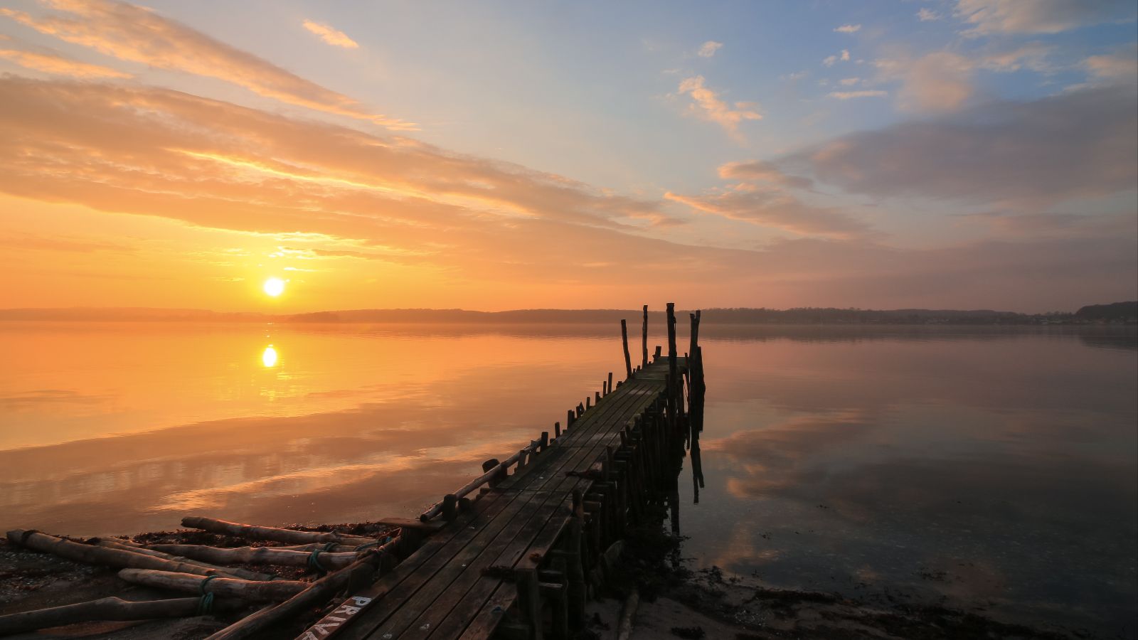 Holzsteg an einem See im Sonnenuntergang. 