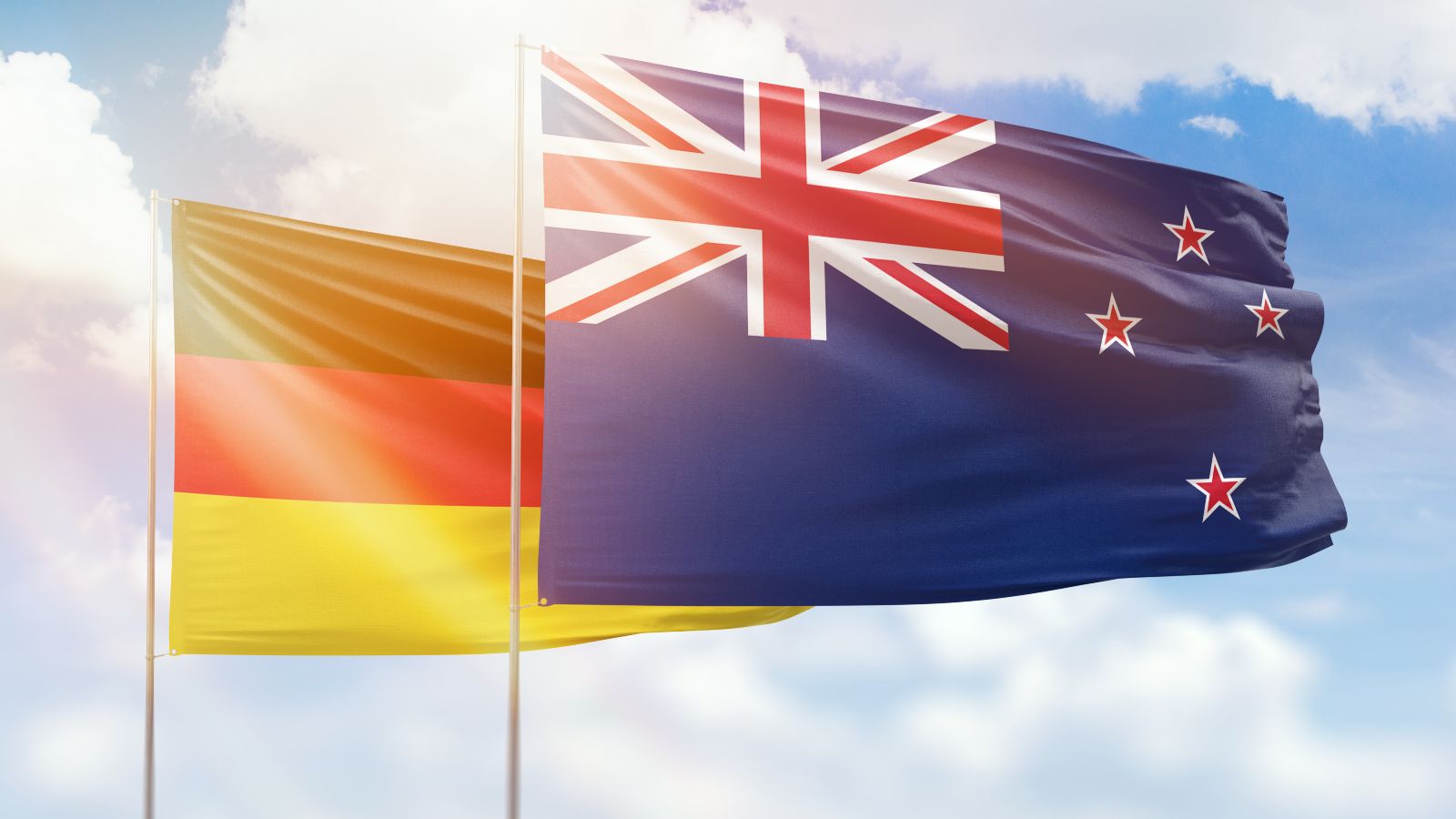 Sunny blue sky and flags of new zealand and germany