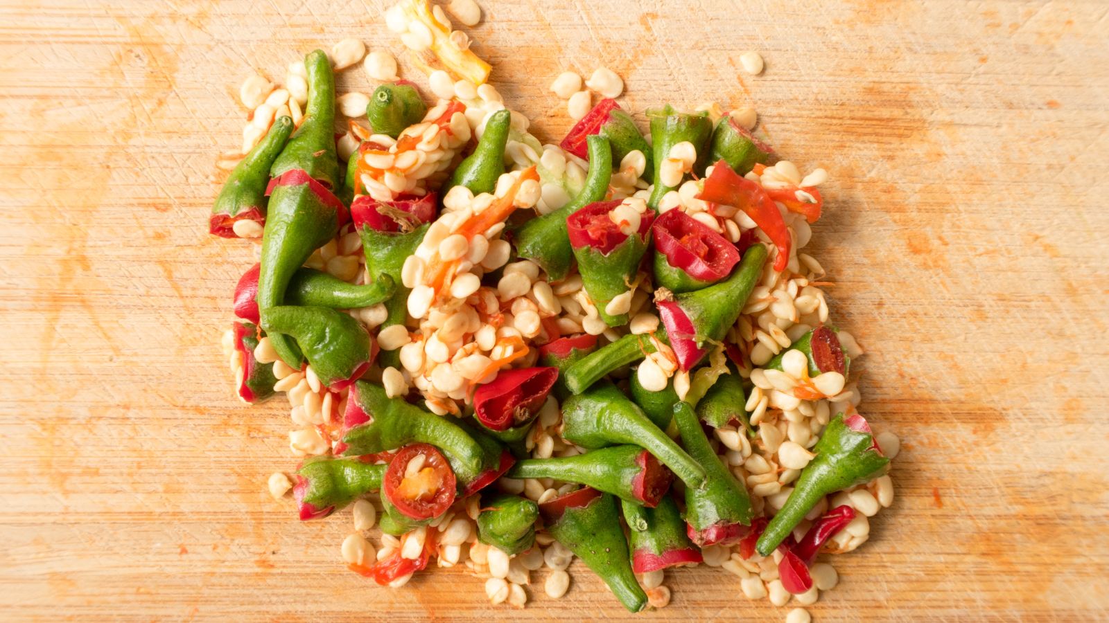 Gehackte Reste von roten Chilischoten auf einem Holzbrett.