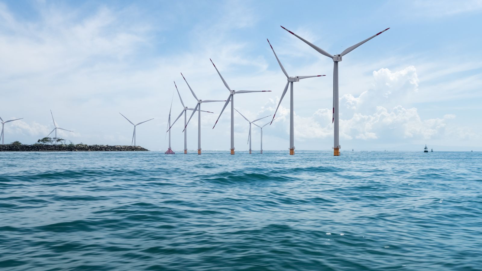 Mehrere Windräder stehen im Ozean.