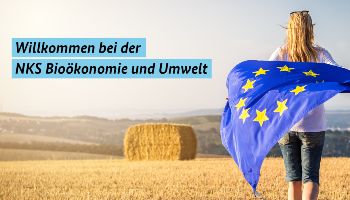 Eine Frau die mit einer Europaflagge über ein abgeerntetes Feld läuft.