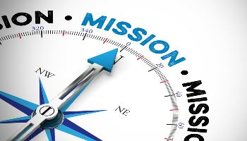 A blue and black compass needle on a white background points to the word Mission written in blue. 