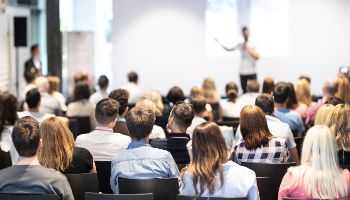 Bild eines Konferenzvortrages mit Blick auf den Sprecher auf dem Podium.