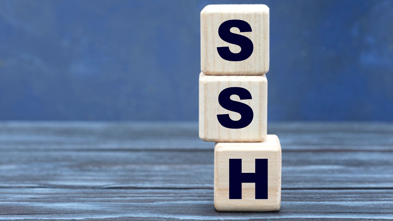 Drei gestapelte Holzwürfel die von oben nach unten den Begriff SSH bilden.